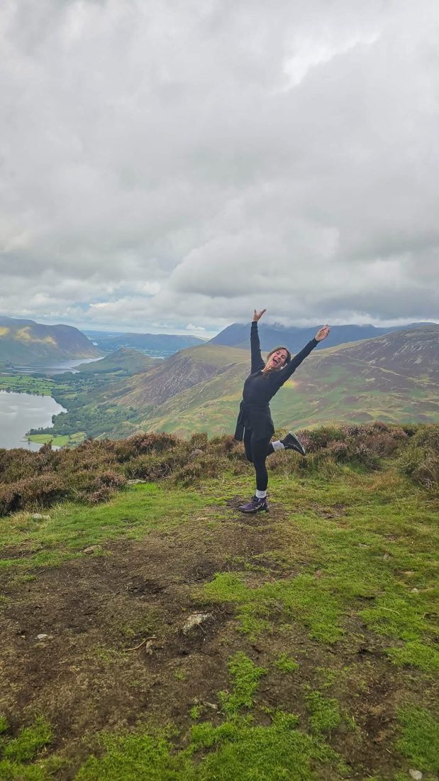 A walker celebrating on a heathery fell top above Crummock Water