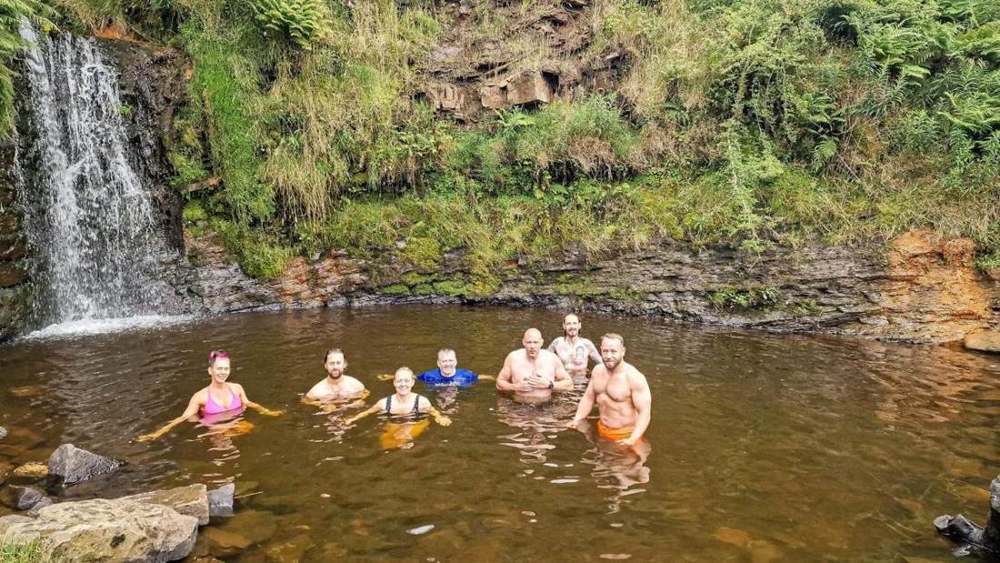 A group of Solna walkers chest-deep in a mountain pool