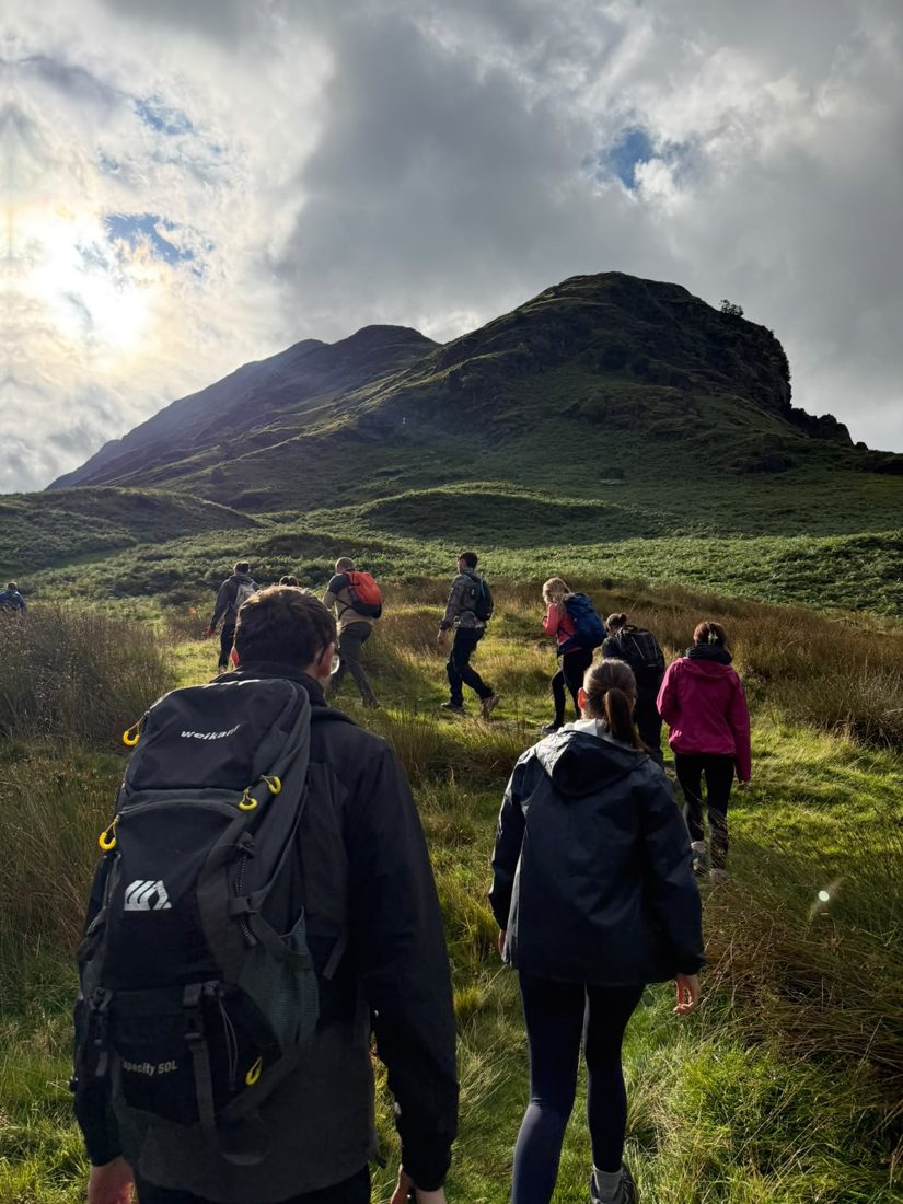 Solna walkers setting off across the valley towards the ridge with the sun breaking through the cloud