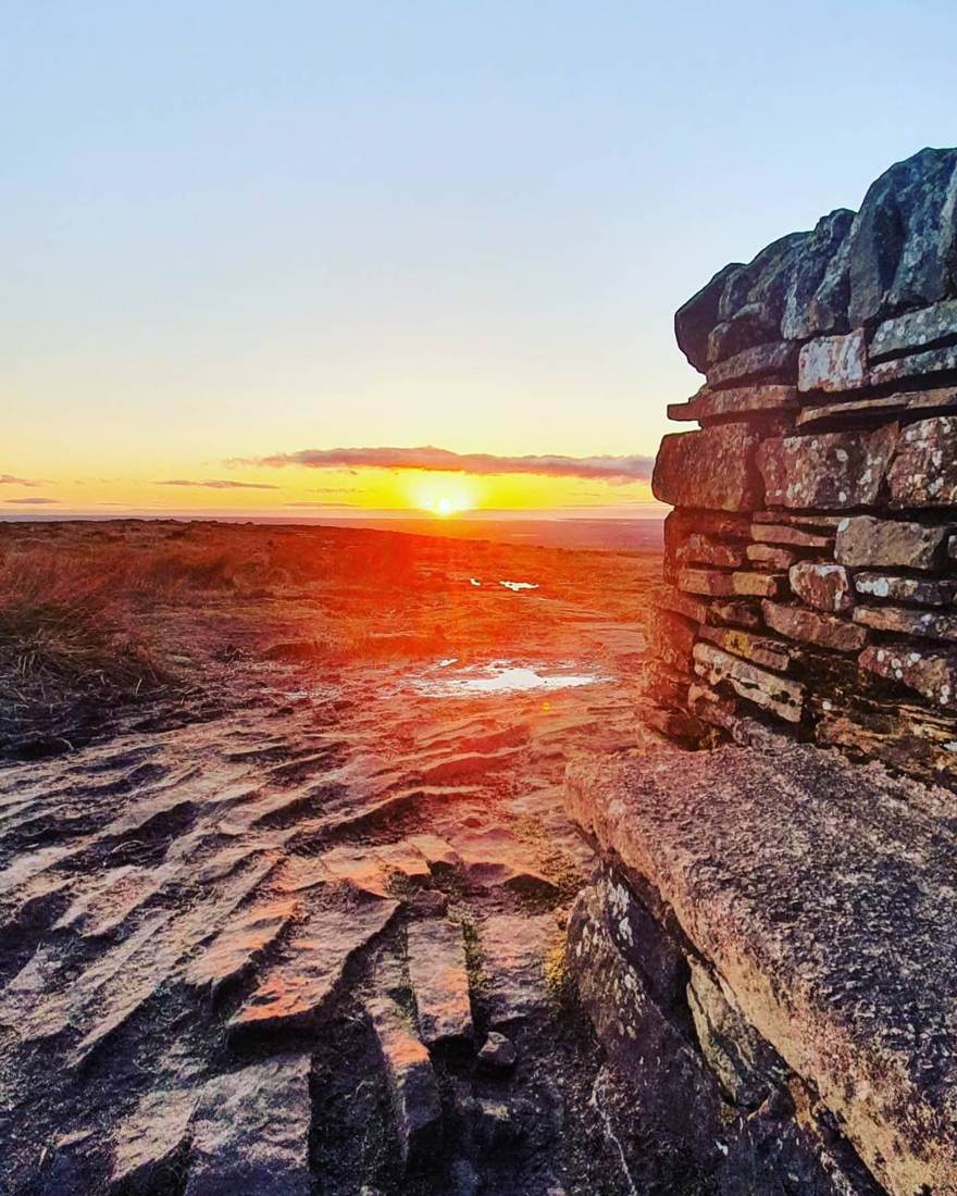 Sunrise breaking over a Lake District summit cairn