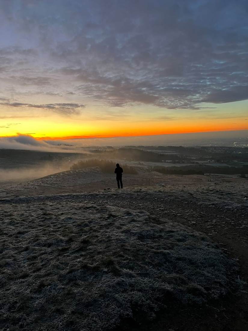 Walkers silhouetted against a sunrise on a Lake District fell
