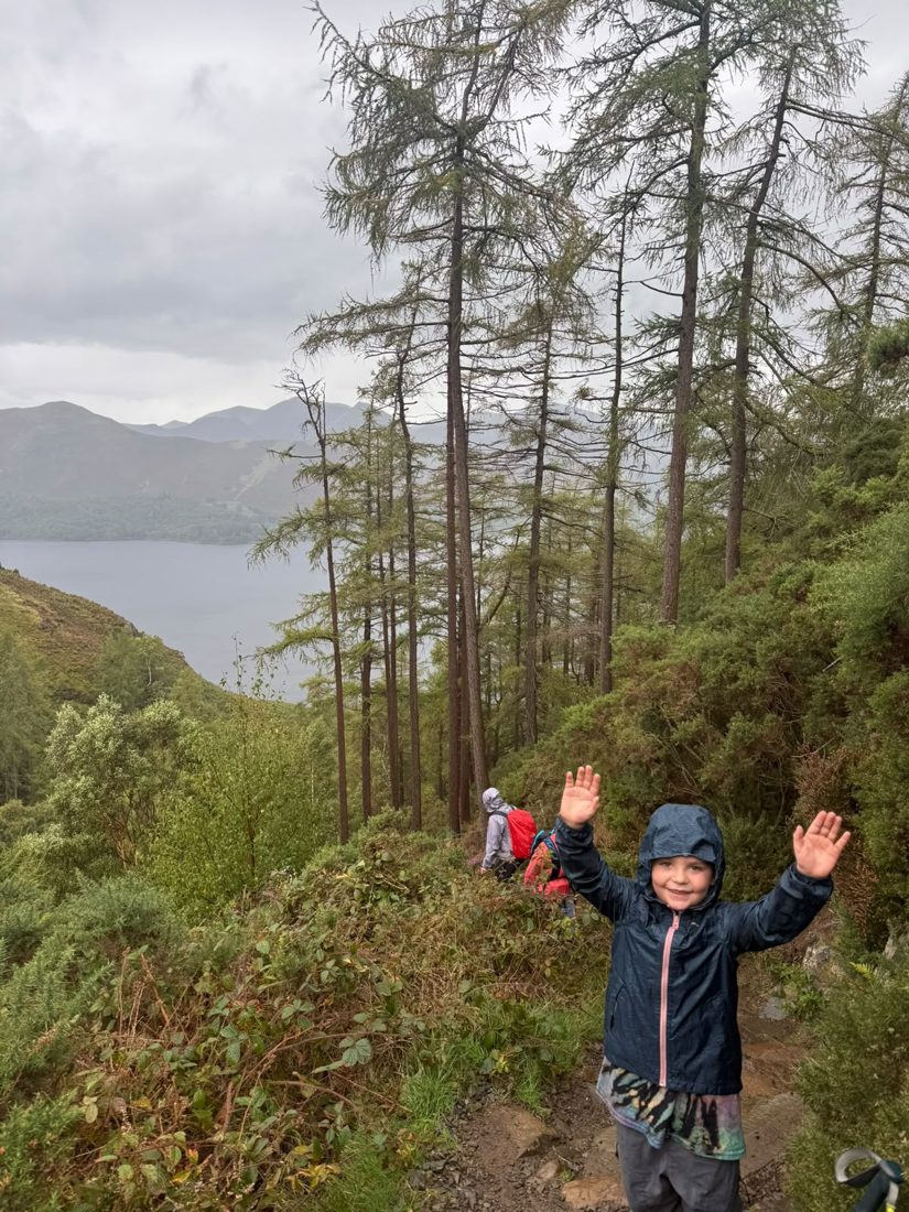 A young Solna walker waving on the path up Walla Crag, Derwent Water and the north-western fells behind